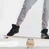A person is balancing on a wooden balance board. Produktbild-Vorschau