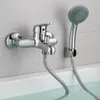 A chrome bathtub faucet with a handheld showerhead mounted on a tiled wall above a bathtub filled with water. Podgląd zdjęcia produktu