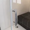 A close-up view of a shower cabin with a chrome handle and a dark tiled bench. Produktbild-Vorschau