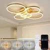 A modern LED ceiling light with multiple rings, shown in a room setting with different lighting options displayed below, along with a remote control and a smartphone app interface. Náhled obrázku produktu