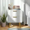 A white nightstand with gold legs and handles, decorated with a vase of flowers and a vintage radio. Produktbild-Vorschau