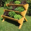 A tiered wooden planter filled with various herbs and lettuces, set in a garden. Produktbild-Vorschau