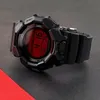 A black digital watch with a red display is shown on a dark surface. Produktbild-Vorschau