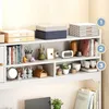 A white bookshelf unit filled with various decorative items and storage boxes, placed against a light-colored wall. Podgląd zdjęcia produktu