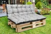 A grey cushion set on a wooden pallet bench in a garden setting. Náhľad obrázku produktu