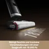A close-up shot of a wet and dry vacuum cleaner head cleaning a spill on a brown floor. The vacuum is shown in action, with liquid being suctioned up. Text indicating suction power is visible on the floor. Produktbild-Vorschau
