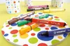 Several colored markers are arranged on a circular mat with colorful polka dots, with two patterned cups in the background. Anteprima dell’immagine prodotto