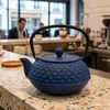 A blue cast iron teapot sits on a counter in what appears to be a cafe or restaurant. Podgląd zdjęcia produktu