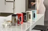 A row of colorful kitchen canisters on a countertop with a person in the background. Produktbild-Vorschau