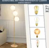 A floor lamp with three white globe shades and a gold stand, shown next to a couch. The right side of the image displays four different types of E27 light bulbs. Podgląd zdjęcia produktu