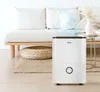 A white dehumidifier is placed on a rug in a living room next to a couch. Produktbild-Vorschau