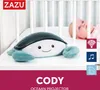 A plush toy turtle with a projected light pattern and a baby in the background, placed in a crib. Náhled obrázku produktu