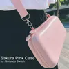 A person wearing black pants and a white shirt is carrying a pink Nintendo Switch case with a pink strap. Produktbild-Vorschau