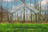 An outdoor scene with a metal and mesh enclosure set up on a grassy area, surrounded by trees. Produktbild-Vorschau