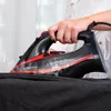 A person is ironing black fabric with a steam iron. Náhľad obrázku produktu