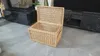 A wicker chest with its lid open, placed on a tiled floor in front of a dark marble entertainment unit. Voir les images du produit