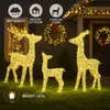 Three illuminated reindeer figures are placed on a lawn in front of a house decorated with Christmas lights and wreaths. Produktbild-Vorschau