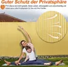 A mother and daughter are doing yoga on a mat in front of a yellow privacy fence. Produktbild-Vorschau
