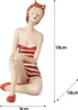 A figurine of a woman in a red and white striped swimsuit and a red polka dot headscarf, sitting with her legs crossed. Voir les images du produit