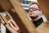 A man wearing safety glasses is working with wooden beams. Produktbild-Vorschau