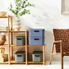Storage boxes on a wooden shelf next to a chair. Produktbild-Vorschau