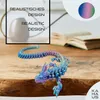 A 3D printed dragon figurine with a gradient color scheme is displayed on a wooden surface, with a blurred background of a book and a vase. Produktbild-Vorschau