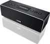 A black Canton Musicbox XS portable Bluetooth speaker is shown on a reflective white surface. Produktbild-Vorschau