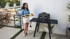 A woman is holding a tray of vegetables next to a black electric grill on a patio. Voir les images du produit