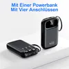 Two black power banks are displayed on a white surface against a white background. One power bank is lying flat, showing its integrated cables and ports. The other power bank is standing upright, displaying a digital screen and a brand logo. Produktbild-Vorschau