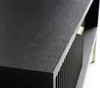 A close-up view of the corner of a black wooden highboard with a fluted front and a gold handle. Produktbild-Vorschau