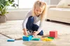 A young girl is playing with colorful blocks on a rug in a living room. Anteprima dell’immagine prodotto