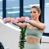 A woman is performing a dumbbell exercise in a gym. Produktbild-Vorschau