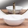 A close-up view of a marble-patterned vessel sink with a gold faucet, reflected in a mirror. Produktbild-Vorschau