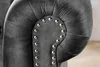 A close-up view of the tufted armrest of a gray velvet armchair, featuring decorative silver studs. Produktbild-Vorschau