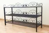 A black metal shoe rack with decorative scrollwork on a light-colored wall and wooden floor. Produktbild-Vorschau