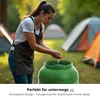 A woman washing her hands in a green barrel at a campsite. Produktbild-Vorschau
