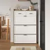 A white shoe cabinet with brown accents is shown in a room with wooden floors and chairs. Anteprima dell’immagine prodotto
