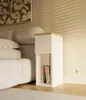 A bedside table next to a bed in a bedroom. Anteprima dell’immagine prodotto