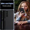 A young woman is holding a black phone case in a cafe setting. Voir les images du produit