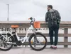 A man stands next to an electric bicycle on a wooden pier. Produktbild-Vorschau