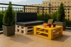 A balcony setting with pallet furniture, drinks, and a laptop. Anteprima dell’immagine prodotto