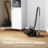 Two vacuum cleaners are shown in a room, one inside a cabinet and another on the floor. Text is present at the bottom of the image. Produktbild-Vorschau
