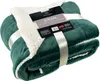 A folded green sherpa blanket with a white fluffy lining, tied with a white ribbon and a product tag. Produktbild-Vorschau