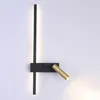 A modern wall lamp with a black vertical bar and a gold adjustable spotlight. Anteprima dell’immagine prodotto