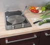 A kitchen counter with a stovetop, cooking pan, and fresh vegetables being prepared. Produktbild-Vorschau