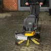A person is using a powered weed brush on a paved surface. Produktbild-Vorschau