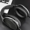 A close-up shot of black headphones resting on a black surface next to a portion of a laptop. Produktbild-Vorschau