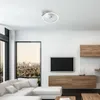 A modern living room with a sectional sofa, television, and a unique ceiling light. Produktbild-Vorschau