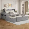 A modern bedroom with a grey platform bed featuring integrated storage and a bench. Produktbild-Vorschau