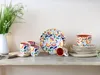 A collection of floral-patterned tableware, including mugs, plates, and bowls, arranged on a wooden shelf. Náhľad obrázku produktu